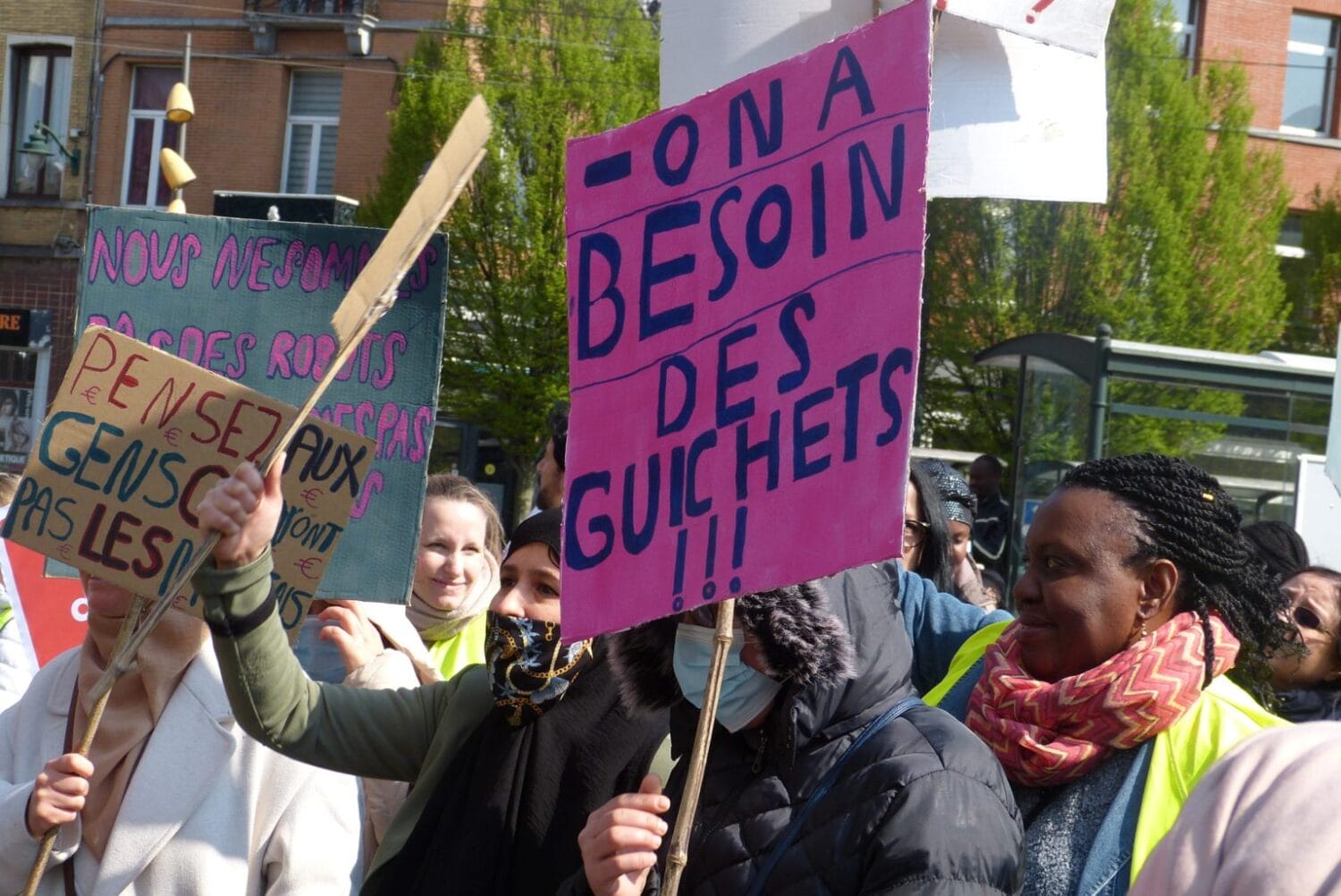 Manifestation contre l'ordonnance Bruxelles numérique. Une personne tient une pancarte affichant "On a besoin des guichets !!!" au premier plan.